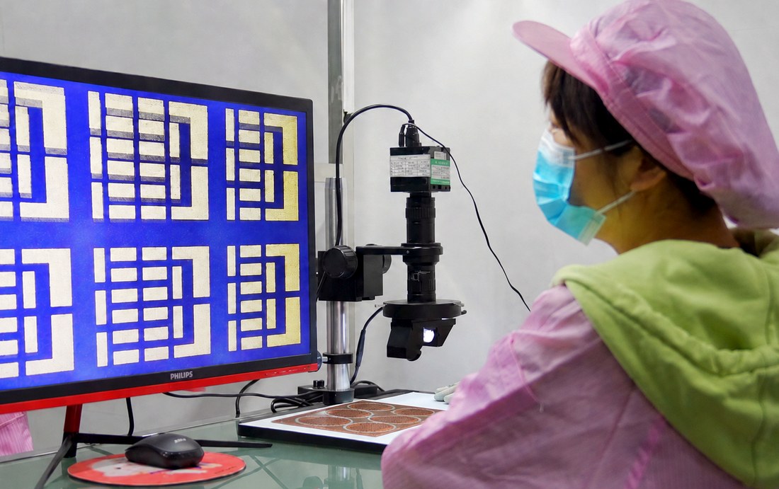 Operator inspecting ceramic circuit patterns with optical inspection equipment
