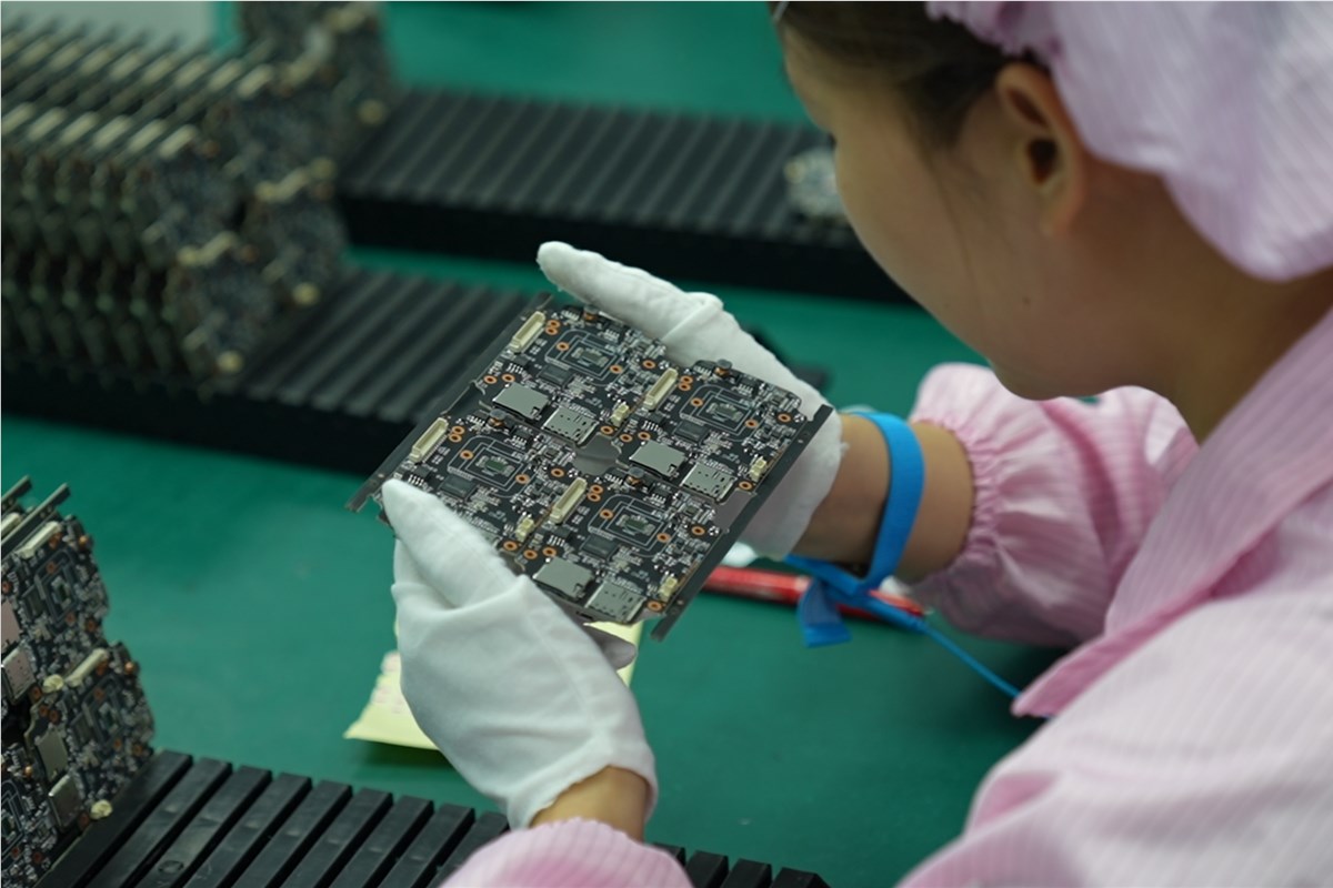 Operator inspecting assembled PCB panels during quality control